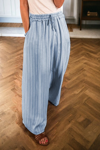 Person wearing light blue striped pants on a wooden floor