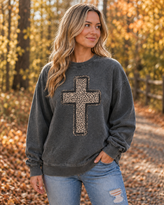 Woman wearing a charcoal grey vintage wash sweatshirt with a frayed leopard print cross patch, styled with light wash jeans