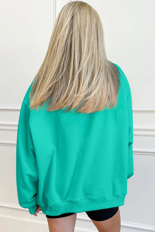 Person wearing a teal sweatshirt with a plain background