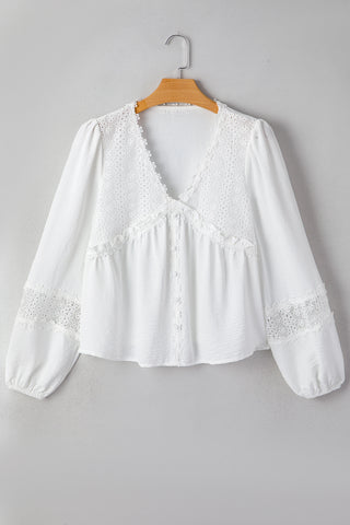 White blouse with lace details on a hanger against a gray background