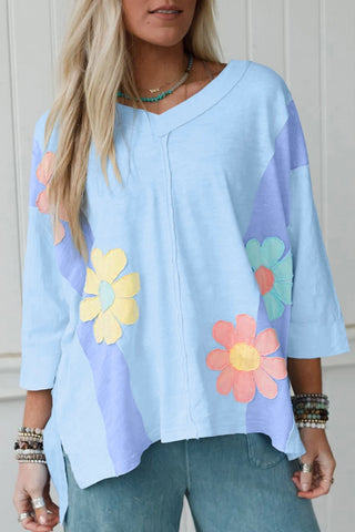 Light blue tunic top with colorful flower patterns worn by a person.