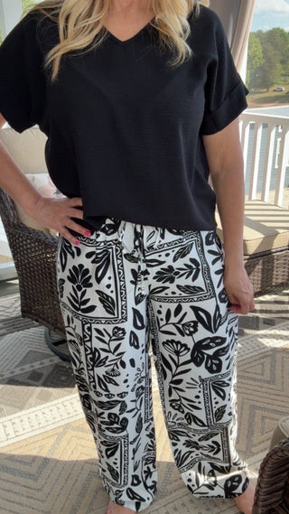 Woman wearing a black top and patterned pants on a patio